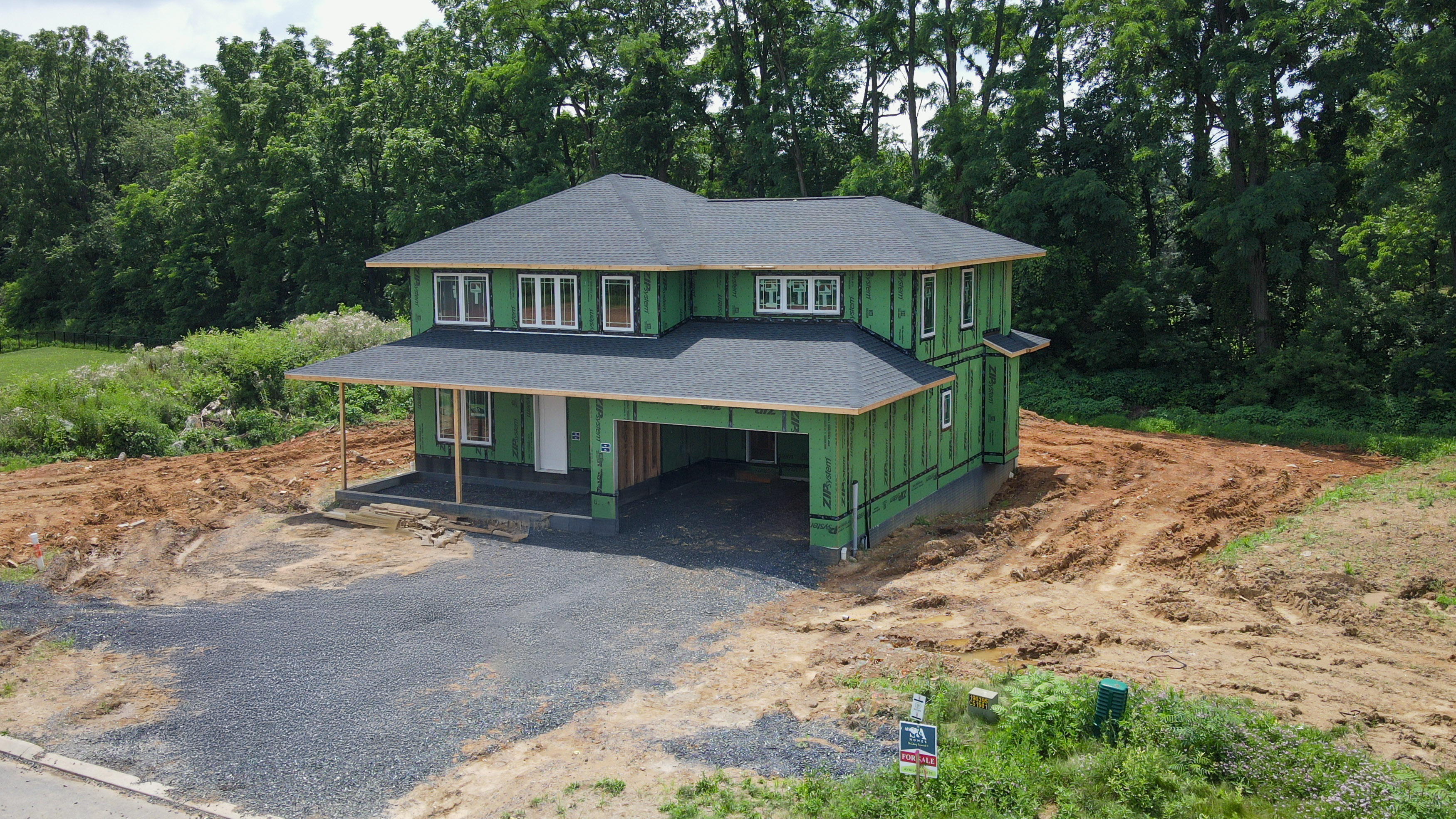 Stage 2 - Framing.jpg: Two-story home framed and weather-protected with roof installed, showcasing structural progress before exterior finishes.