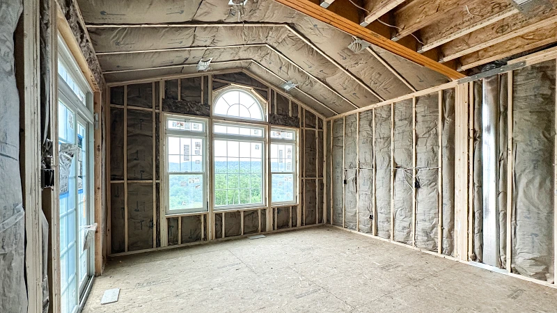 Stage 3- Insulation.jpg: Interior room with exposed framing and insulation installed in walls and vaulted ceiling, improving comfort and energy efficiency.