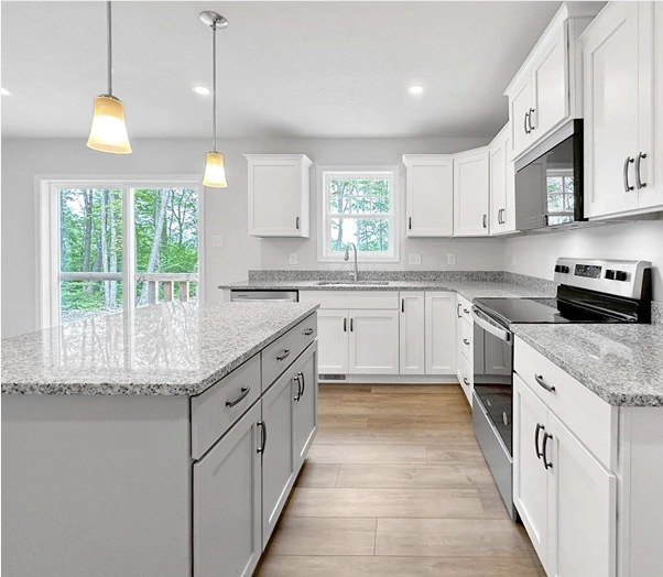 Newly made kitchen with pendant lights, light gray countertops, and white cabinetry