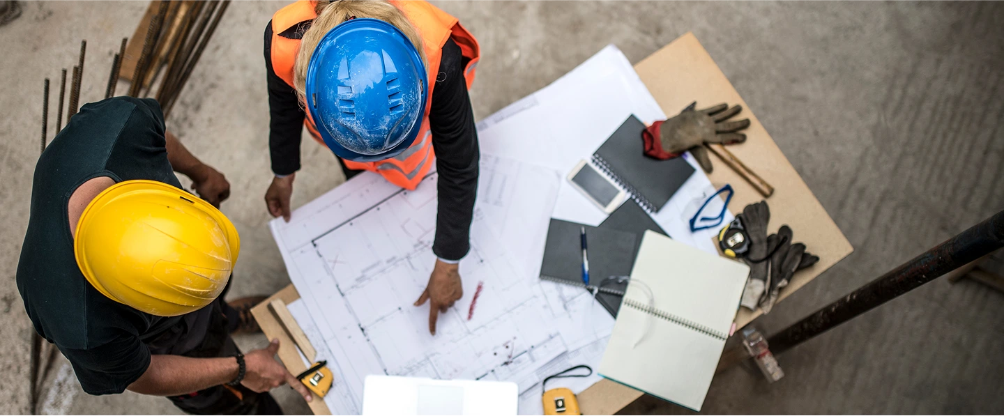 Constructions workers pointing at their documents with their hard hats on