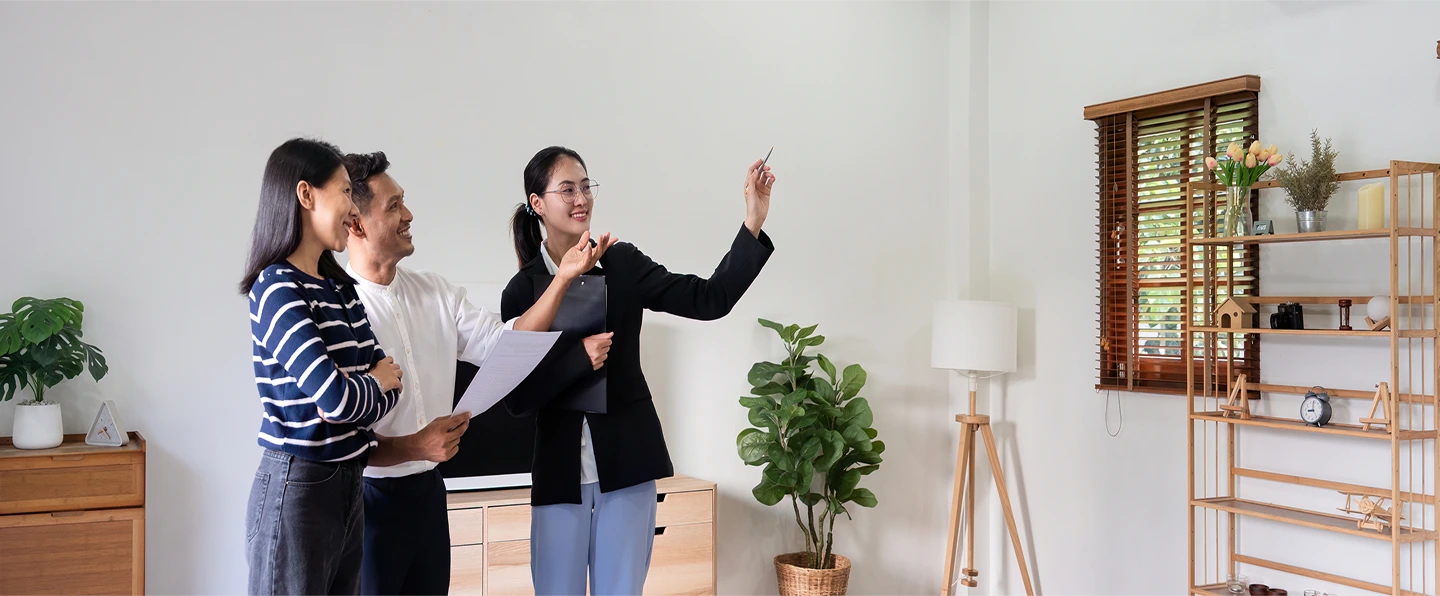 Three individuals in a room pointing at a wall learning about their new home